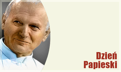 Na obrazku przedstawiona jest twarz Papieża Jana Pawła II w białej sutannie, widać białą koloratkę. W dolnym prawym rogu znajduje się napis Dzień Papieski.